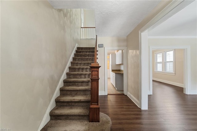 staircase with crown molding, hardwood / wood-style floors, and a textured ceiling