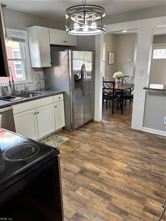 kitchen with appliances with stainless steel finishes, dark hardwood / wood-style flooring, white cabinetry, and sink