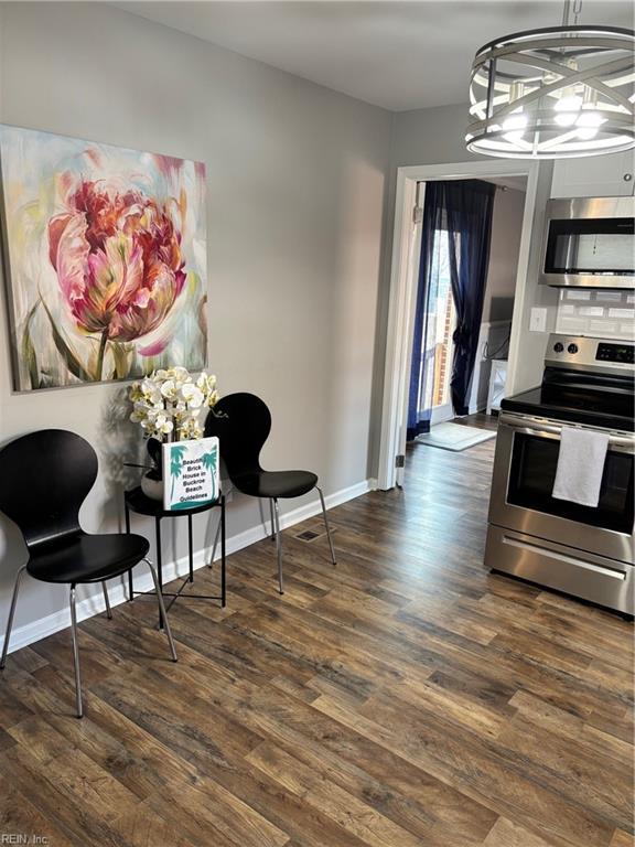 kitchen featuring appliances with stainless steel finishes, dark hardwood / wood-style flooring, and an inviting chandelier