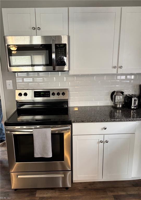 kitchen featuring white cabinetry, dark hardwood / wood-style flooring, dark stone counters, and appliances with stainless steel finishes