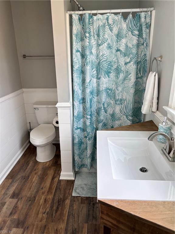 bathroom featuring a shower with curtain, sink, hardwood / wood-style flooring, toilet, and tile walls