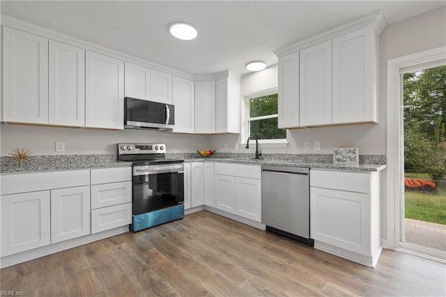 kitchen with white cabinets, light hardwood / wood-style floors, sink, and stainless steel appliances