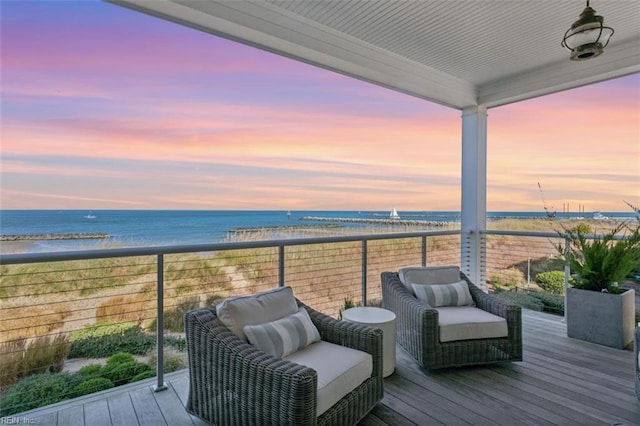 deck at dusk featuring a water view and a view of the beach