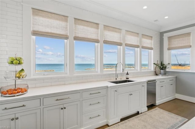 kitchen with decorative backsplash, ornamental molding, sink, a water view, and white cabinets