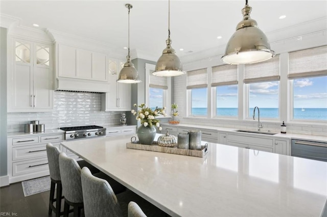 kitchen featuring a wealth of natural light, sink, a water view, and pendant lighting