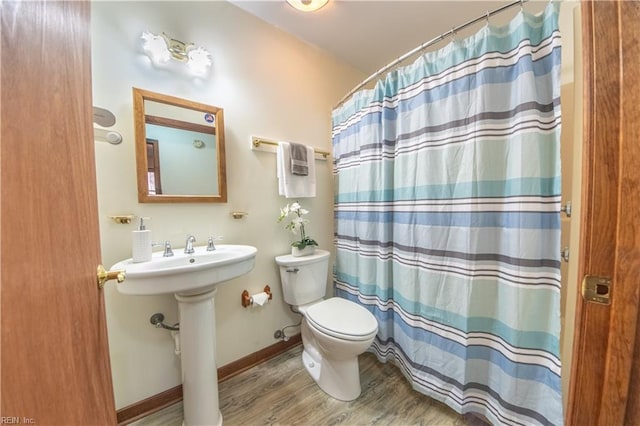 bathroom featuring wood-type flooring, toilet, curtained shower, and sink