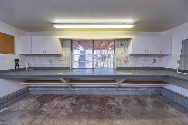 kitchen featuring decorative backsplash, white cabinetry, and concrete flooring