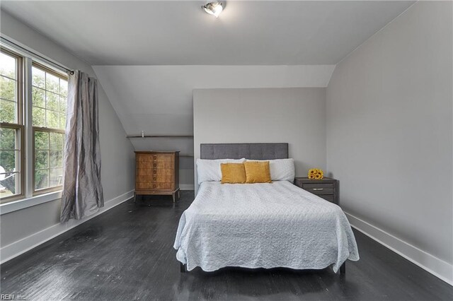 bedroom with dark wood-type flooring and lofted ceiling