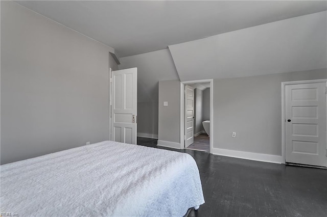 bedroom featuring dark hardwood / wood-style flooring, lofted ceiling, and connected bathroom