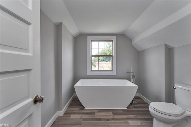 bathroom featuring a washtub, hardwood / wood-style flooring, toilet, and lofted ceiling