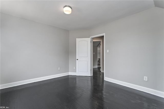 empty room with dark wood-type flooring and lofted ceiling