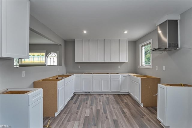 kitchen with white cabinets, light hardwood / wood-style flooring, and wall chimney exhaust hood