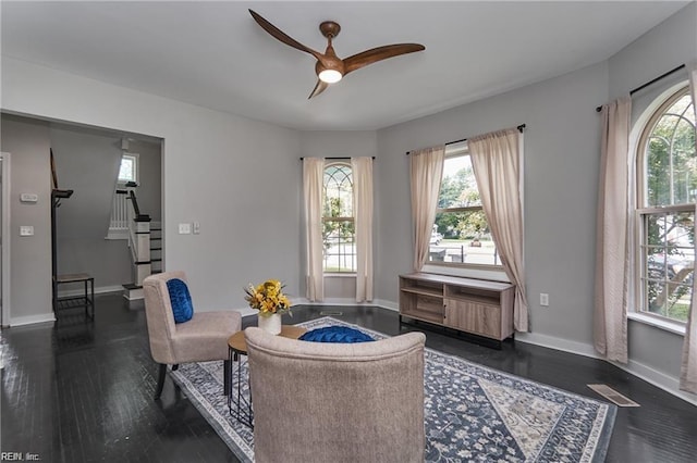 living area with ceiling fan, dark hardwood / wood-style flooring, and a wealth of natural light