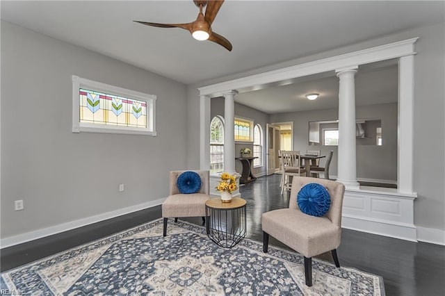 living area featuring decorative columns, ceiling fan, and hardwood / wood-style floors