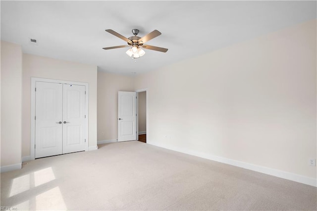 unfurnished bedroom featuring ceiling fan, light carpet, and a closet