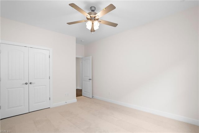 unfurnished bedroom featuring ceiling fan, a closet, and light carpet