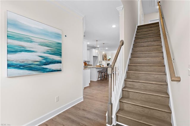 stairs featuring hardwood / wood-style floors and crown molding