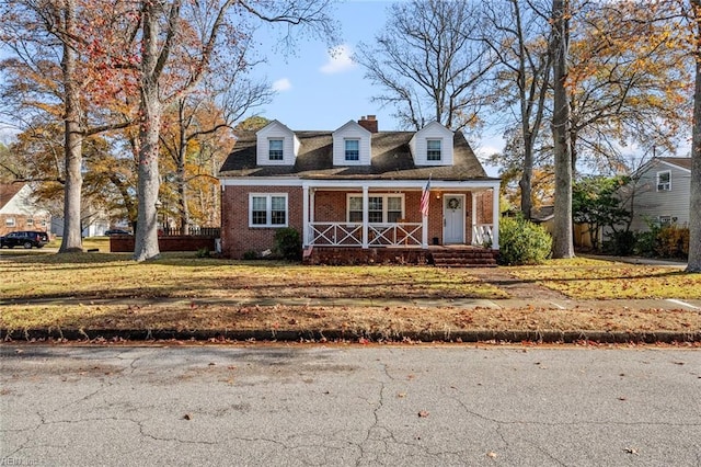 new england style home featuring covered porch and a front lawn