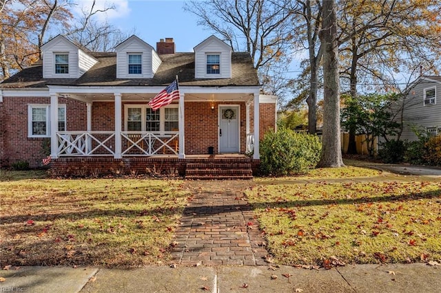 cape cod-style house featuring a porch and a front lawn