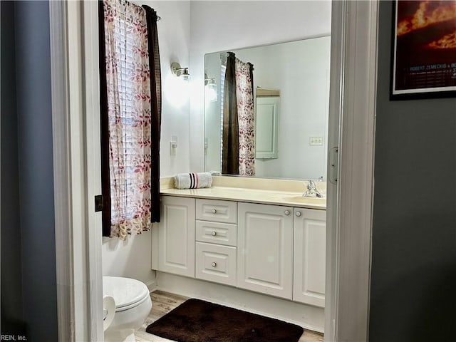 bathroom featuring wood-type flooring, vanity, and toilet