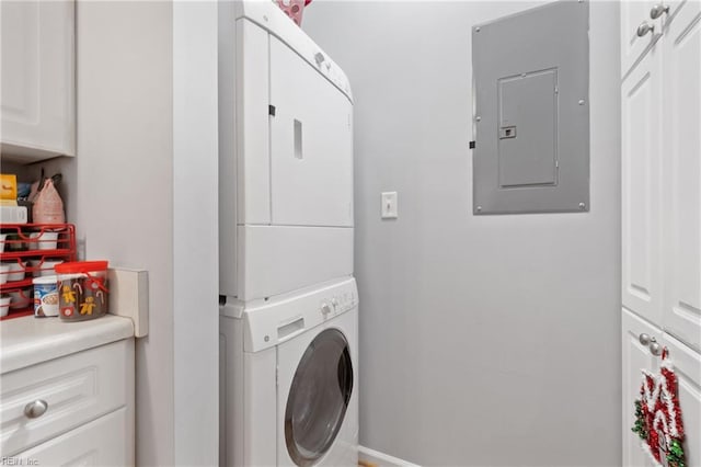 laundry room featuring cabinets, stacked washer / dryer, and electric panel