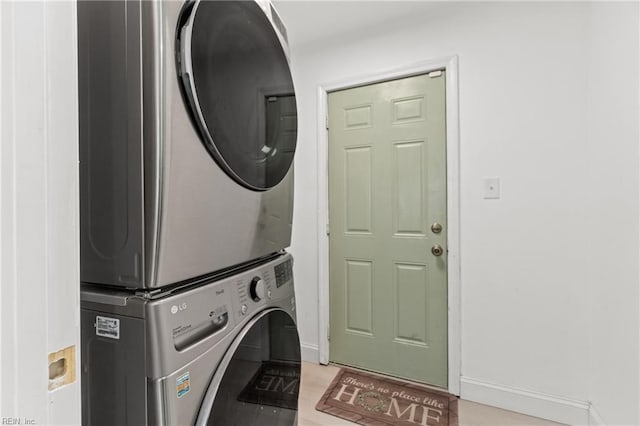 laundry room with stacked washing maching and dryer and light hardwood / wood-style flooring