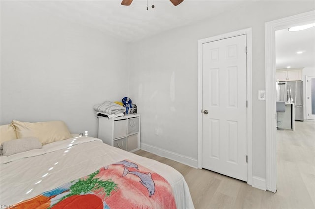 bedroom featuring light hardwood / wood-style floors, stainless steel refrigerator, and ceiling fan