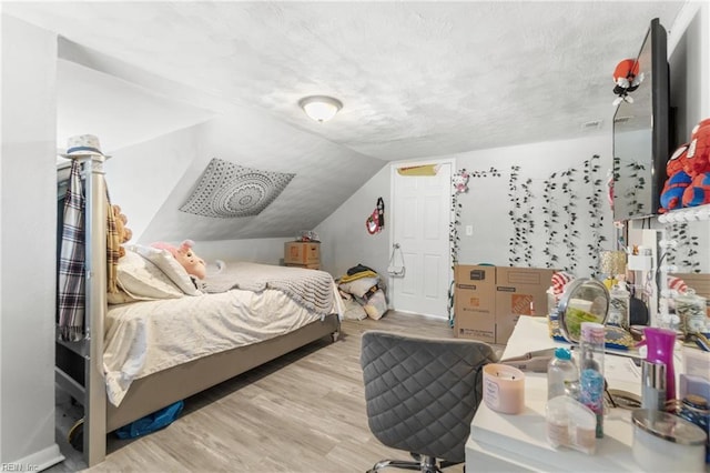 bedroom with vaulted ceiling and light hardwood / wood-style flooring