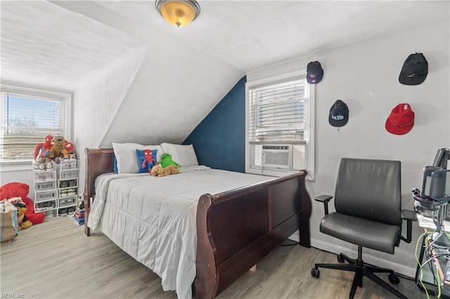 bedroom with light hardwood / wood-style flooring, cooling unit, and lofted ceiling