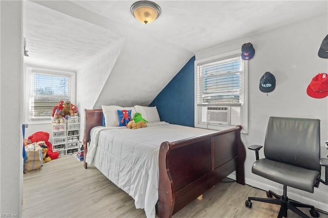 bedroom featuring cooling unit, light wood-type flooring, and vaulted ceiling