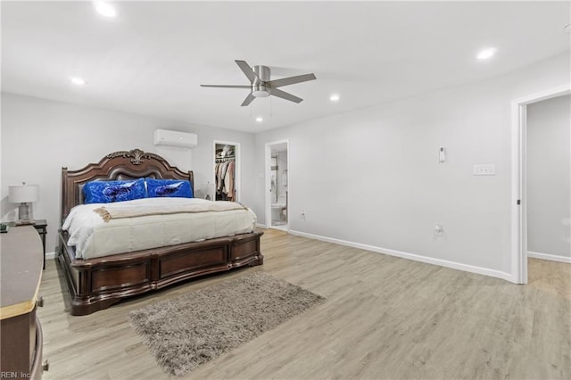 bedroom featuring a wall unit AC, a walk in closet, a closet, and light hardwood / wood-style flooring