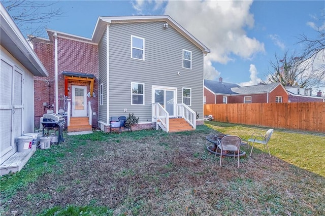 rear view of property featuring a yard and an outdoor fire pit