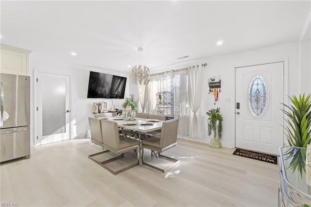 dining space featuring light wood-type flooring and a chandelier