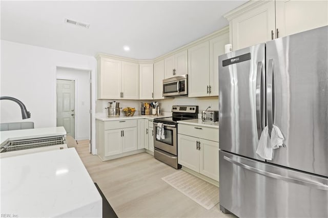 kitchen with light wood-type flooring, sink, and appliances with stainless steel finishes