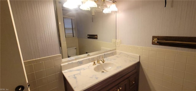 bathroom featuring toilet, tile walls, and vanity