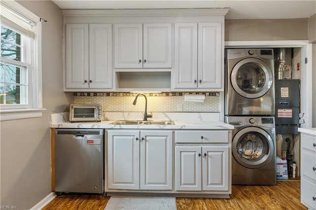 laundry room with light hardwood / wood-style floors, stacked washer / drying machine, and sink