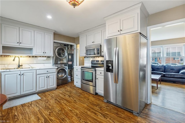 kitchen featuring white cabinets, sink, stacked washer / dryer, and appliances with stainless steel finishes