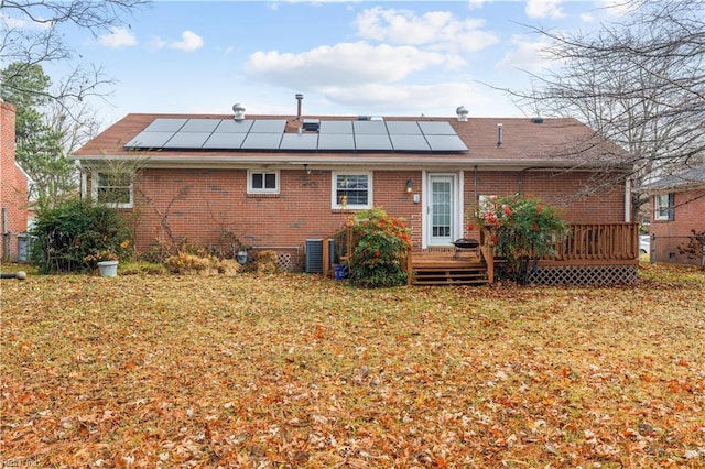 rear view of property featuring solar panels, a yard, cooling unit, and a deck