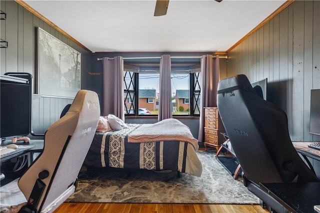 bedroom featuring ceiling fan, wooden walls, wood-type flooring, and ornamental molding