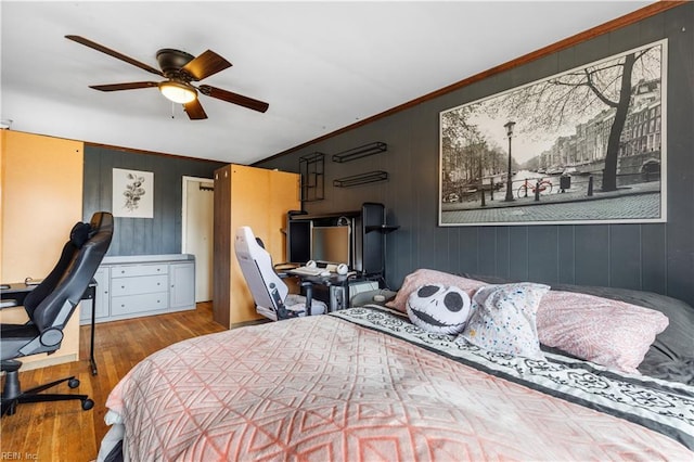 bedroom with ceiling fan, wooden walls, light hardwood / wood-style floors, and ornamental molding