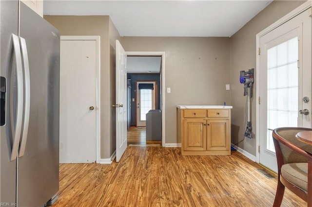 kitchen with stainless steel fridge with ice dispenser and light hardwood / wood-style floors