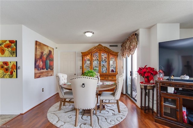 dining space with hardwood / wood-style flooring and a textured ceiling