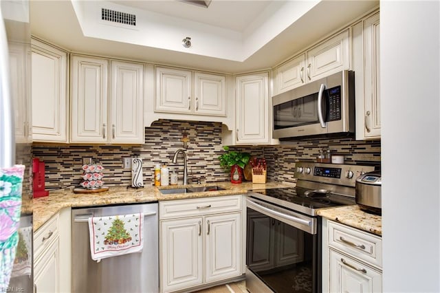 kitchen featuring sink, stainless steel appliances, backsplash, and a tray ceiling