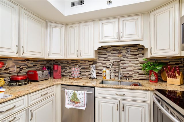 kitchen featuring appliances with stainless steel finishes, white cabinetry, tasteful backsplash, and sink