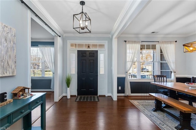 foyer entrance featuring a barn door, dark hardwood / wood-style flooring, and ornamental molding