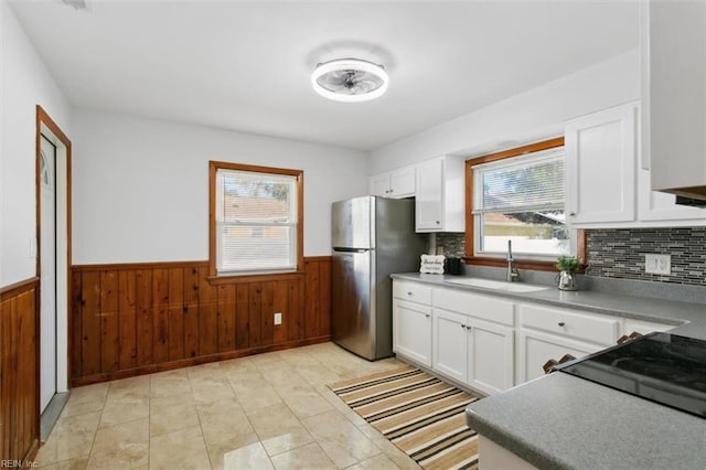 kitchen with backsplash, stainless steel refrigerator, white cabinetry, and sink