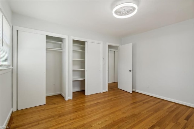 unfurnished bedroom with light hardwood / wood-style floors and multiple closets