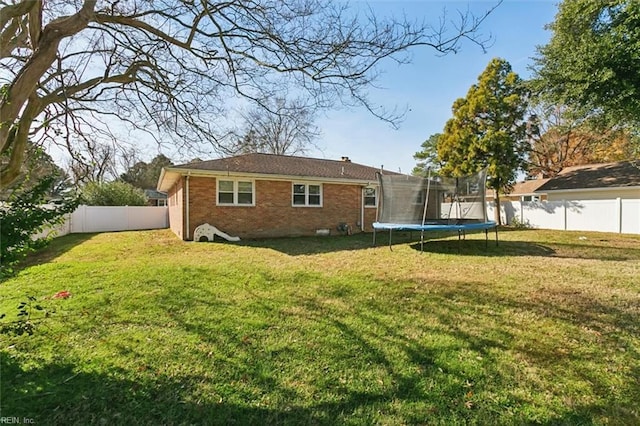 rear view of house with a trampoline and a lawn