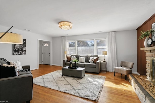 living room featuring a stone fireplace and wood-type flooring