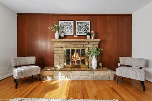 sitting room with a stone fireplace and wood-type flooring